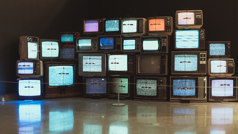 Vintage TVs stacked up on each other with their screens on 